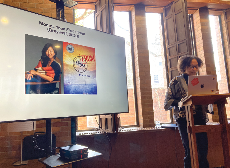 Professor Emily Greenwood delivering a lecture next to a slide showing poet Monica Youn.