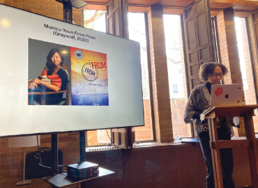 Prof. Emily Greenwood delivering a lecture next to a slide of poet Monica Youn.
